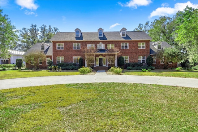 georgian-style home featuring a front lawn and brick siding