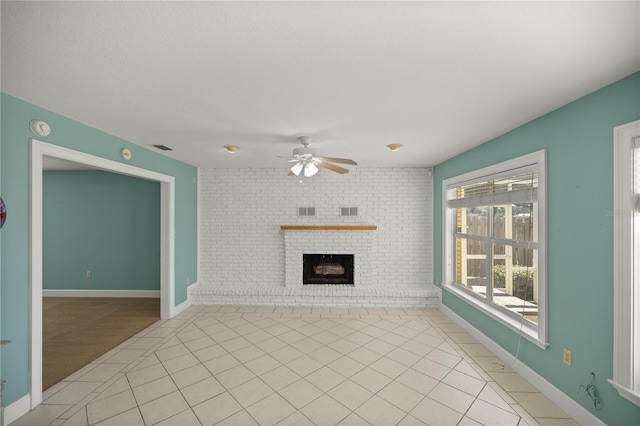 unfurnished living room with ceiling fan, brick wall, light tile patterned floors, and a fireplace