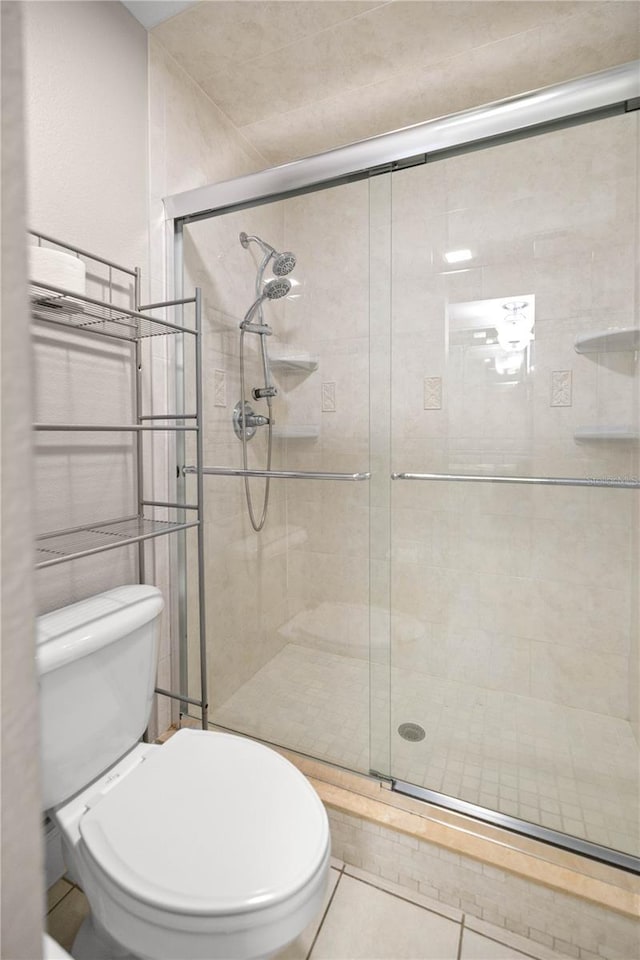 bathroom featuring toilet, tile patterned flooring, and a shower with door