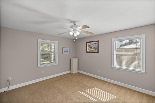 spare room featuring light carpet, plenty of natural light, and ceiling fan