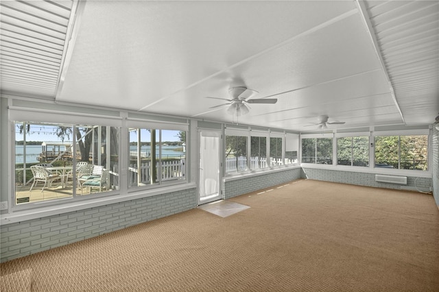 unfurnished sunroom with plenty of natural light, an AC wall unit, ceiling fan, and a water view