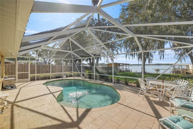 view of swimming pool featuring a patio area, glass enclosure, and a water view