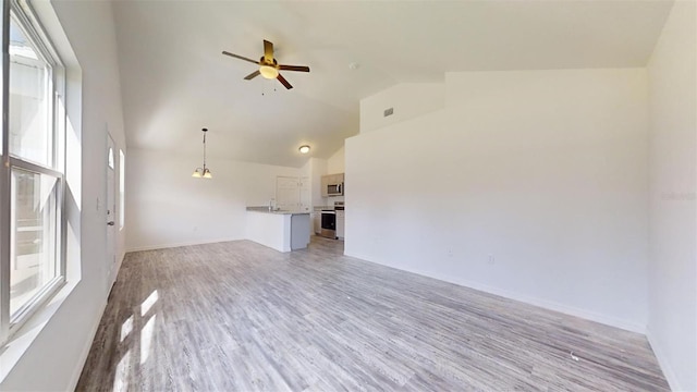 unfurnished living room with ceiling fan, high vaulted ceiling, a healthy amount of sunlight, and light wood-type flooring