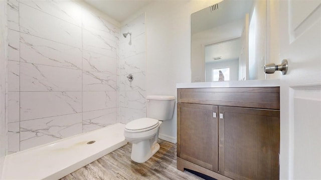 bathroom featuring tiled shower, vanity, toilet, and wood-type flooring