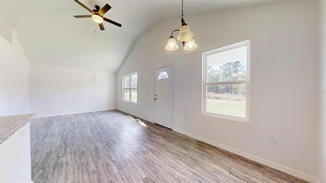 entryway with vaulted ceiling, ceiling fan with notable chandelier, and hardwood / wood-style floors