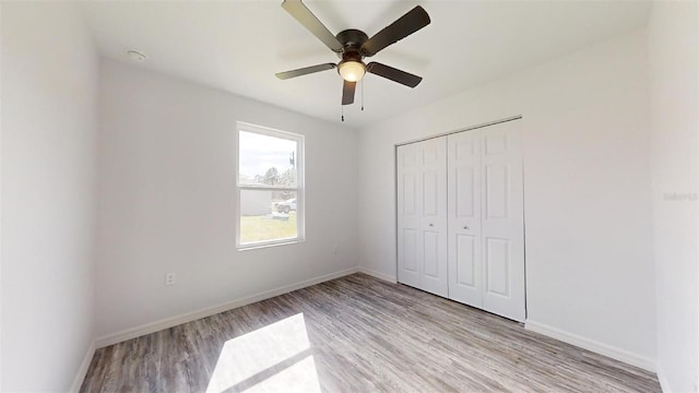 unfurnished bedroom with ceiling fan, a closet, and light wood-type flooring