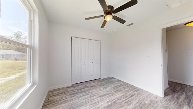 unfurnished bedroom with multiple windows, a closet, and light hardwood / wood-style flooring