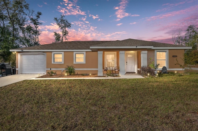 ranch-style house featuring a garage and a lawn