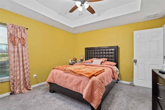 carpeted bedroom featuring a raised ceiling and ceiling fan