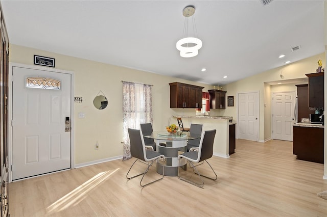 dining room featuring lofted ceiling and light hardwood / wood-style floors