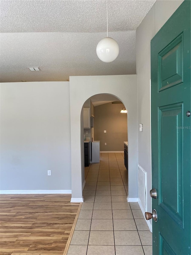 corridor with a textured ceiling and light tile patterned floors