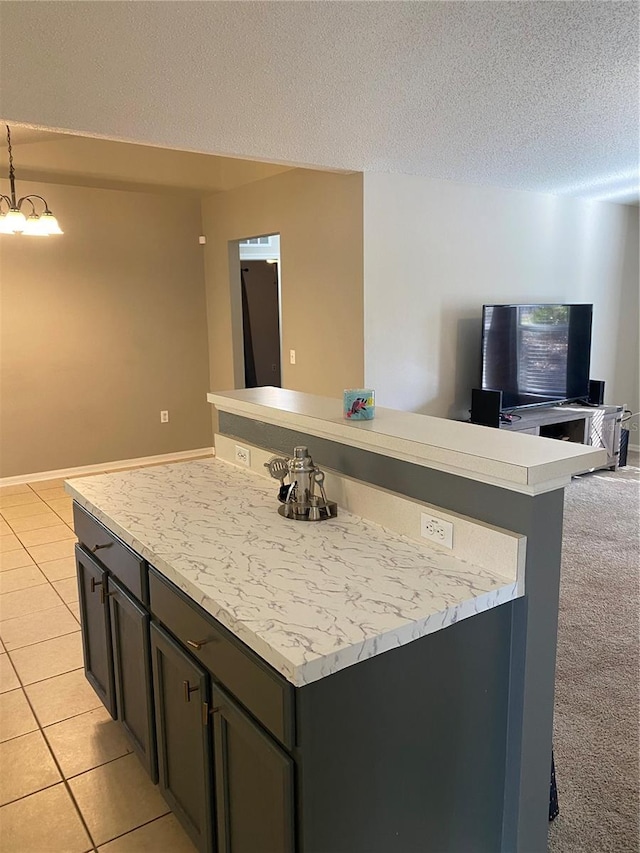 kitchen featuring light tile patterned flooring, a kitchen island, a chandelier, hanging light fixtures, and a textured ceiling