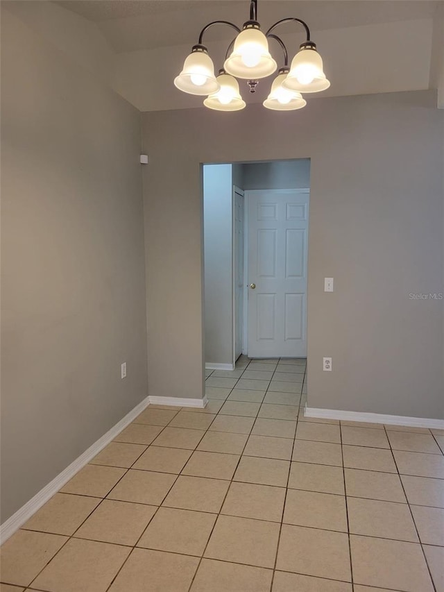 empty room featuring a notable chandelier and light tile patterned floors