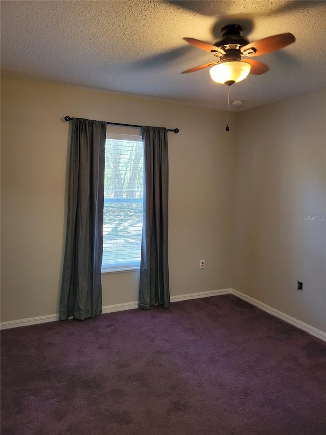 spare room with ceiling fan, a textured ceiling, and dark colored carpet