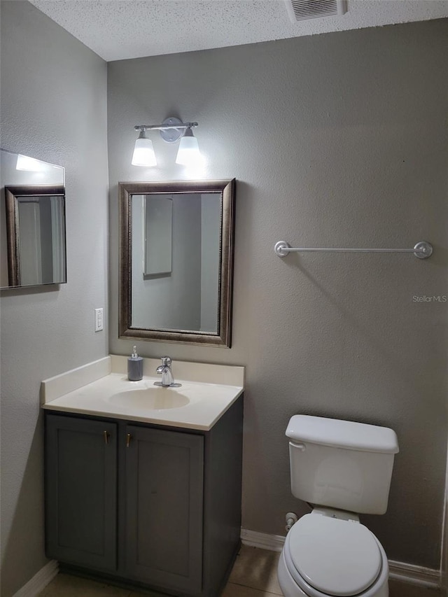 bathroom featuring vanity, a textured ceiling, tile patterned floors, and toilet