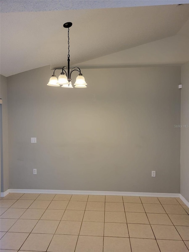 tiled spare room with an inviting chandelier and vaulted ceiling