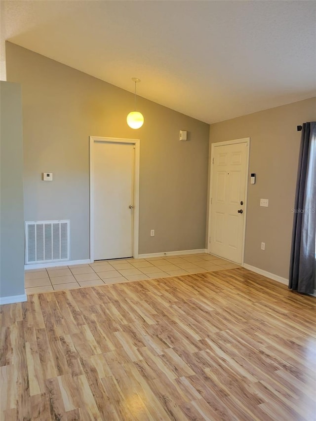 spare room with light tile patterned floors and vaulted ceiling