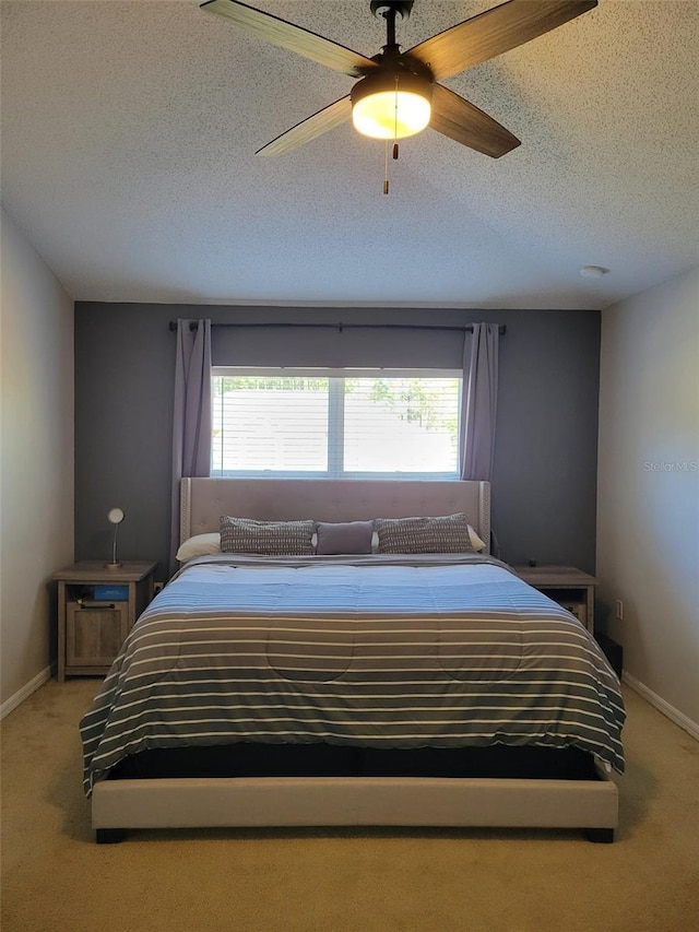 carpeted bedroom featuring ceiling fan and a textured ceiling