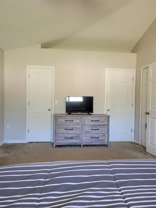 unfurnished bedroom with carpet, lofted ceiling, and a textured ceiling