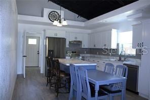 kitchen featuring sink, white cabinets, a kitchen breakfast bar, hanging light fixtures, and stainless steel appliances