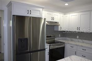 kitchen with white cabinetry, light stone countertops, and appliances with stainless steel finishes