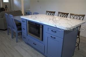 kitchen with hardwood / wood-style flooring, blue cabinetry, a center island, and a kitchen bar