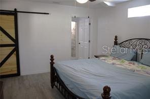 bedroom featuring wood-type flooring, a barn door, and ceiling fan