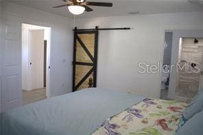 bedroom featuring ceiling fan and a barn door