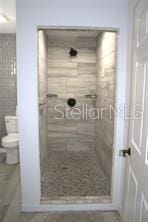 bathroom featuring toilet and a tile shower