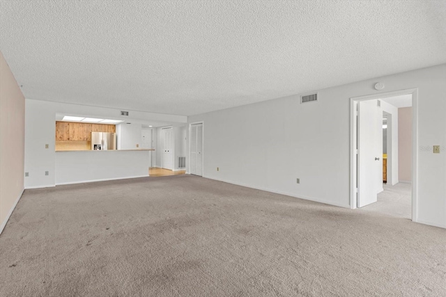 unfurnished living room featuring light carpet and a textured ceiling