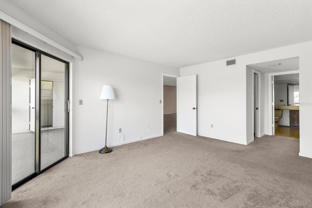 unfurnished bedroom featuring light carpet and a textured ceiling