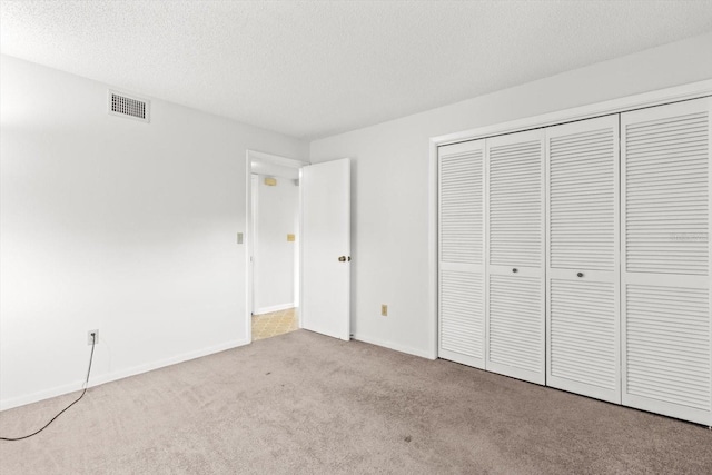 unfurnished bedroom with light colored carpet, a textured ceiling, and a closet