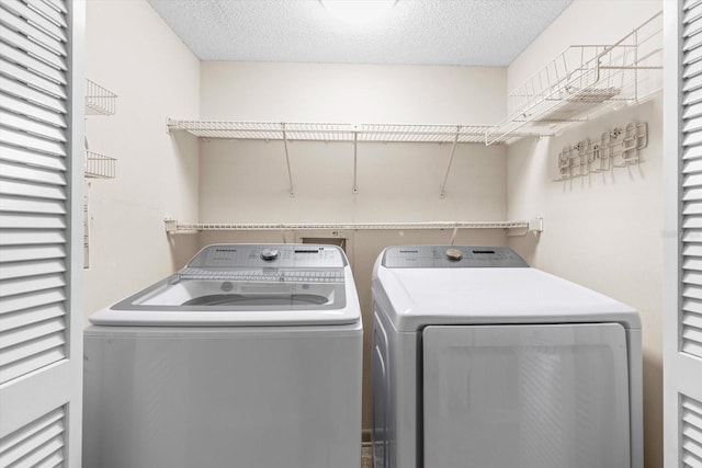 clothes washing area with a textured ceiling and independent washer and dryer