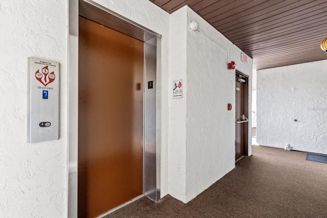 hall with dark colored carpet, elevator, and wood ceiling