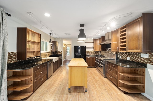 kitchen featuring a center island, butcher block countertops, appliances with stainless steel finishes, light hardwood / wood-style flooring, and wall chimney exhaust hood