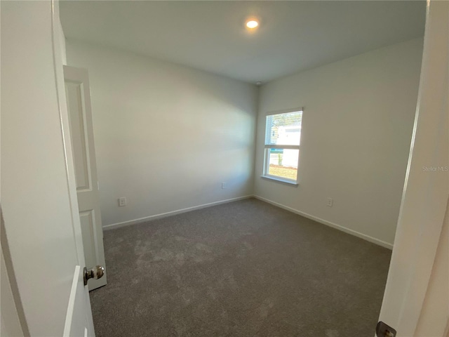 spare room featuring dark carpet