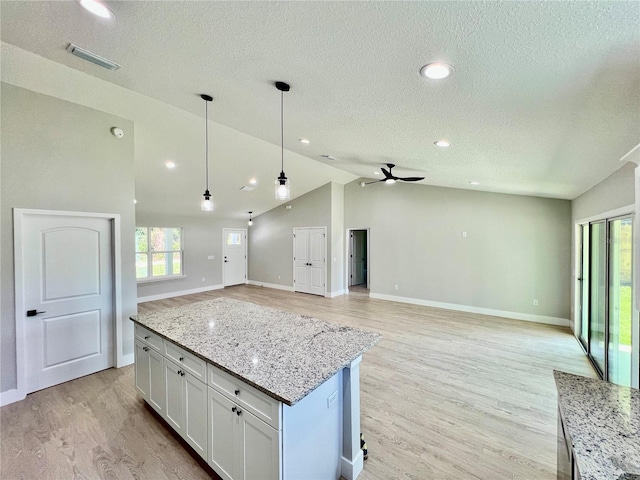 kitchen featuring lofted ceiling, visible vents, open floor plan, white cabinetry, and light wood-type flooring