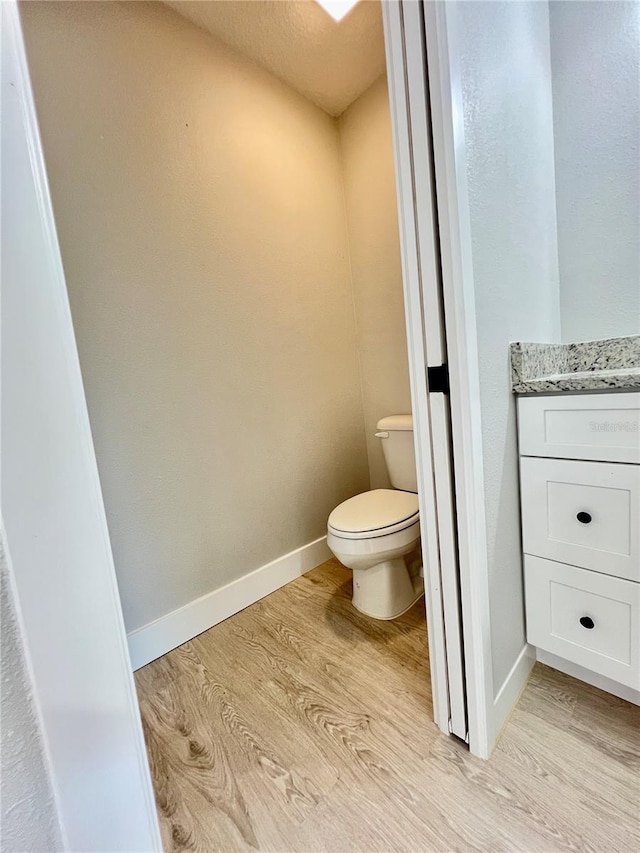 bathroom with vanity, wood finished floors, toilet, and baseboards