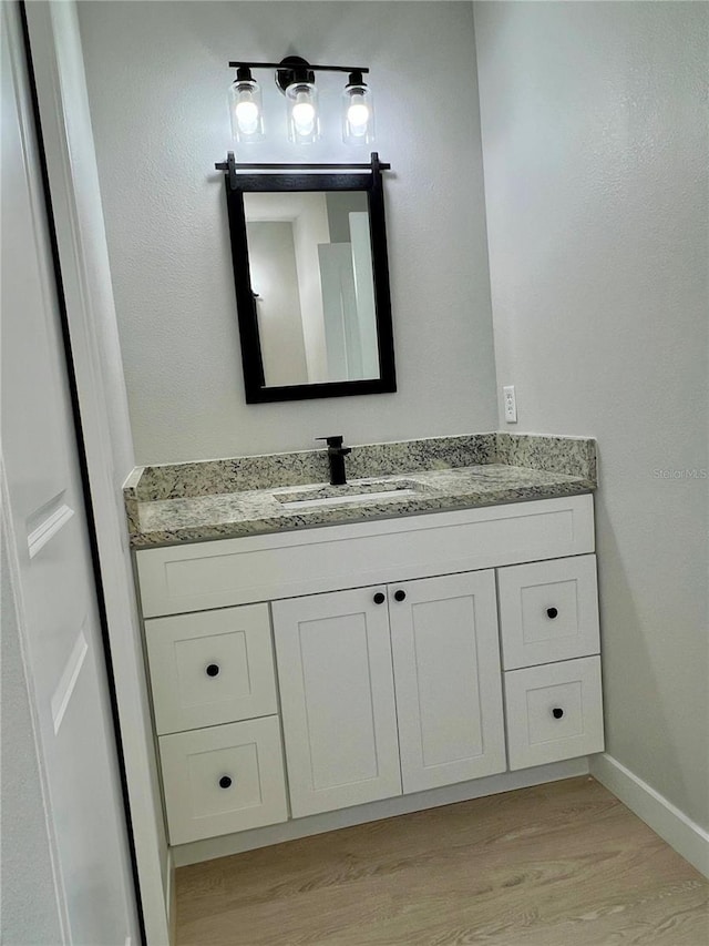 bathroom with baseboards, wood finished floors, and vanity