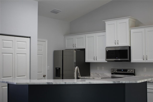 kitchen with stainless steel appliances, kitchen peninsula, vaulted ceiling, and white cabinets