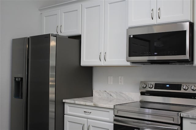 kitchen with white cabinetry, stainless steel appliances, and light stone countertops