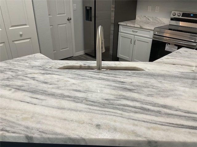 interior space with light stone counters, sink, stainless steel appliances, and white cabinets