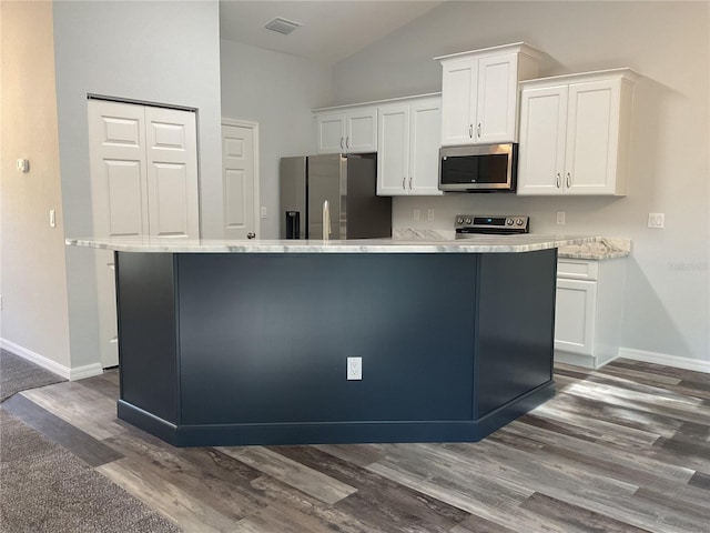 kitchen with vaulted ceiling, a kitchen island, white cabinetry, dark hardwood / wood-style flooring, and stainless steel appliances