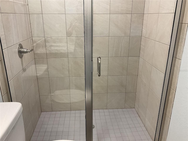 bathroom featuring a shower with door and toilet