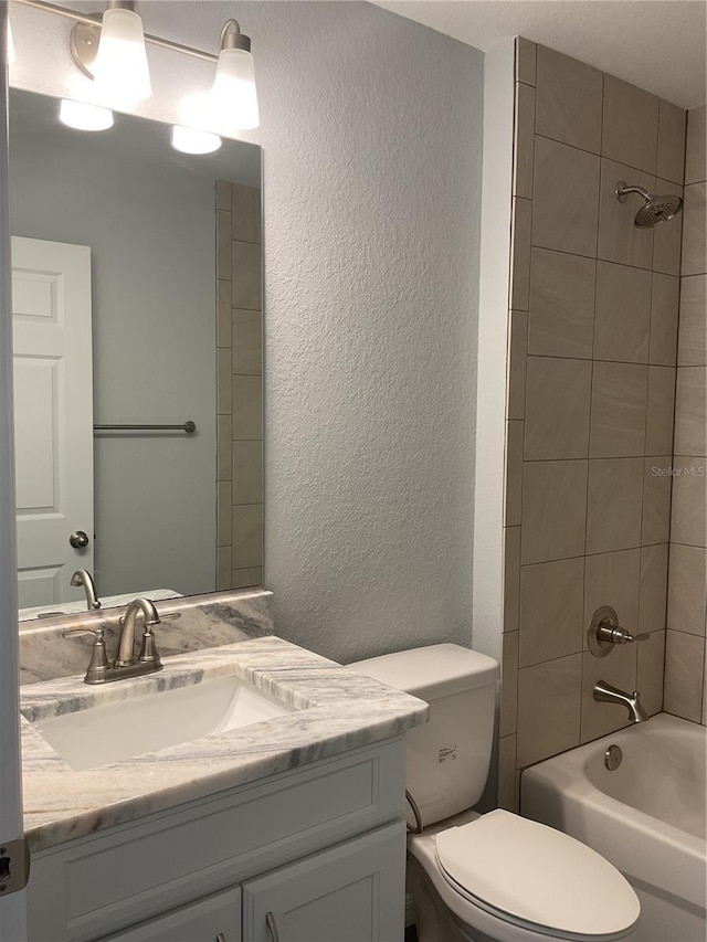 full bathroom with vanity, tiled shower / bath, and toilet