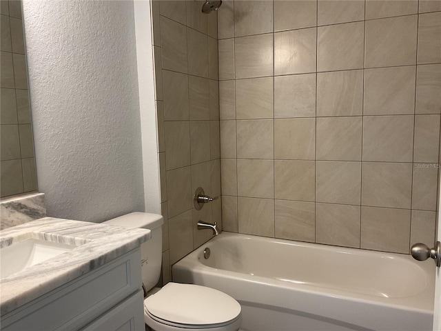 full bathroom featuring vanity, tiled shower / bath, and toilet