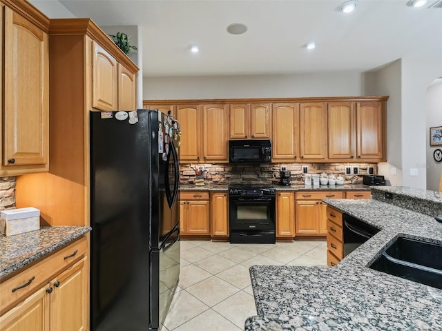 kitchen with dark stone countertops, backsplash, black appliances, and sink