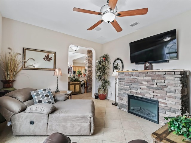 tiled living room featuring a fireplace and ceiling fan