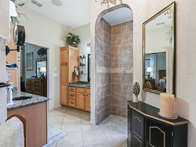 bathroom featuring vanity, tile patterned flooring, and a tile shower