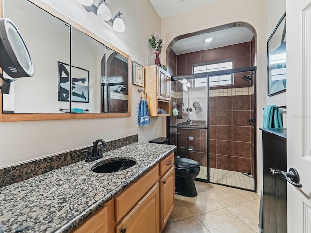 bathroom with walk in shower, vanity, toilet, and tile patterned flooring